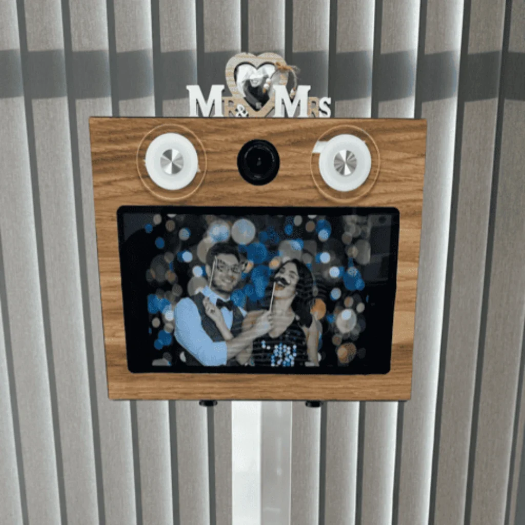 Photobooth avec écran interactif affichant un couple en train de s’amuser avec des accessoires de mariage, proposé par Ouistibox à Poitiers.